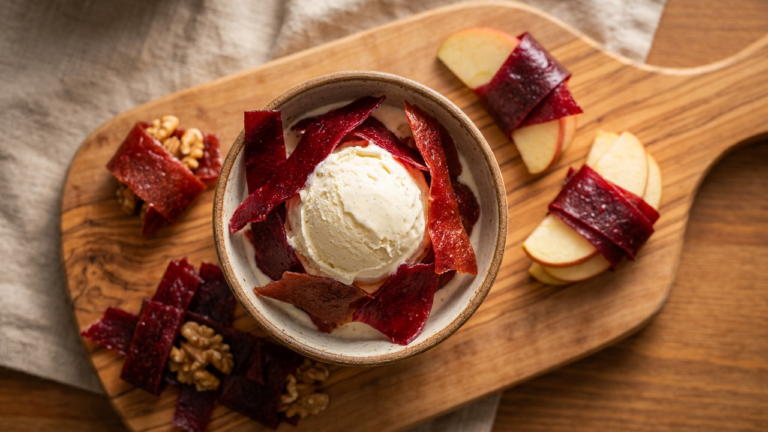 Torn strips of lavashak Persian fruit leather draped over vanilla ice cream