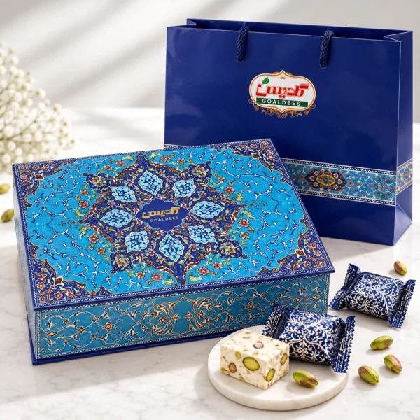 Goaldees 28% pistachio gaz gift box with decorative Persian tile lid, matching gift bag and unwrapped pistachio nougat on marble